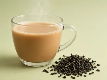 নমুনা ছবি: চা-পাতার পাশে এক কাপ দুধ চা